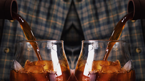 A mirrored image of cold brew being poured into an iced glass.